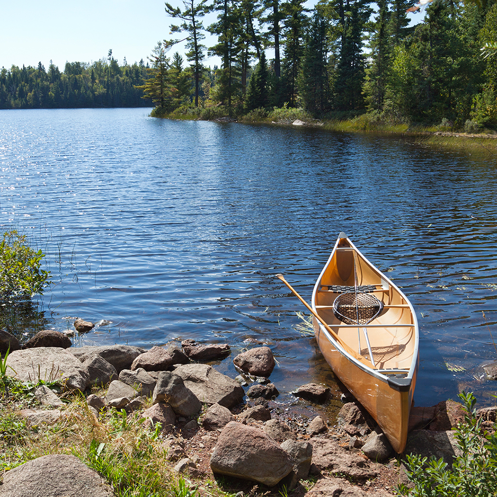 A fisherman’s canoe on rocky shore in northern Minnesota lake A yellow fisherman's canoe on a rocky shore of a northern Minnesota lake